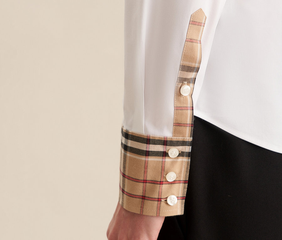 Detail dámské bílé halenky Seidensticker s kostkovaným vzorem na manžetě a knoflíky.