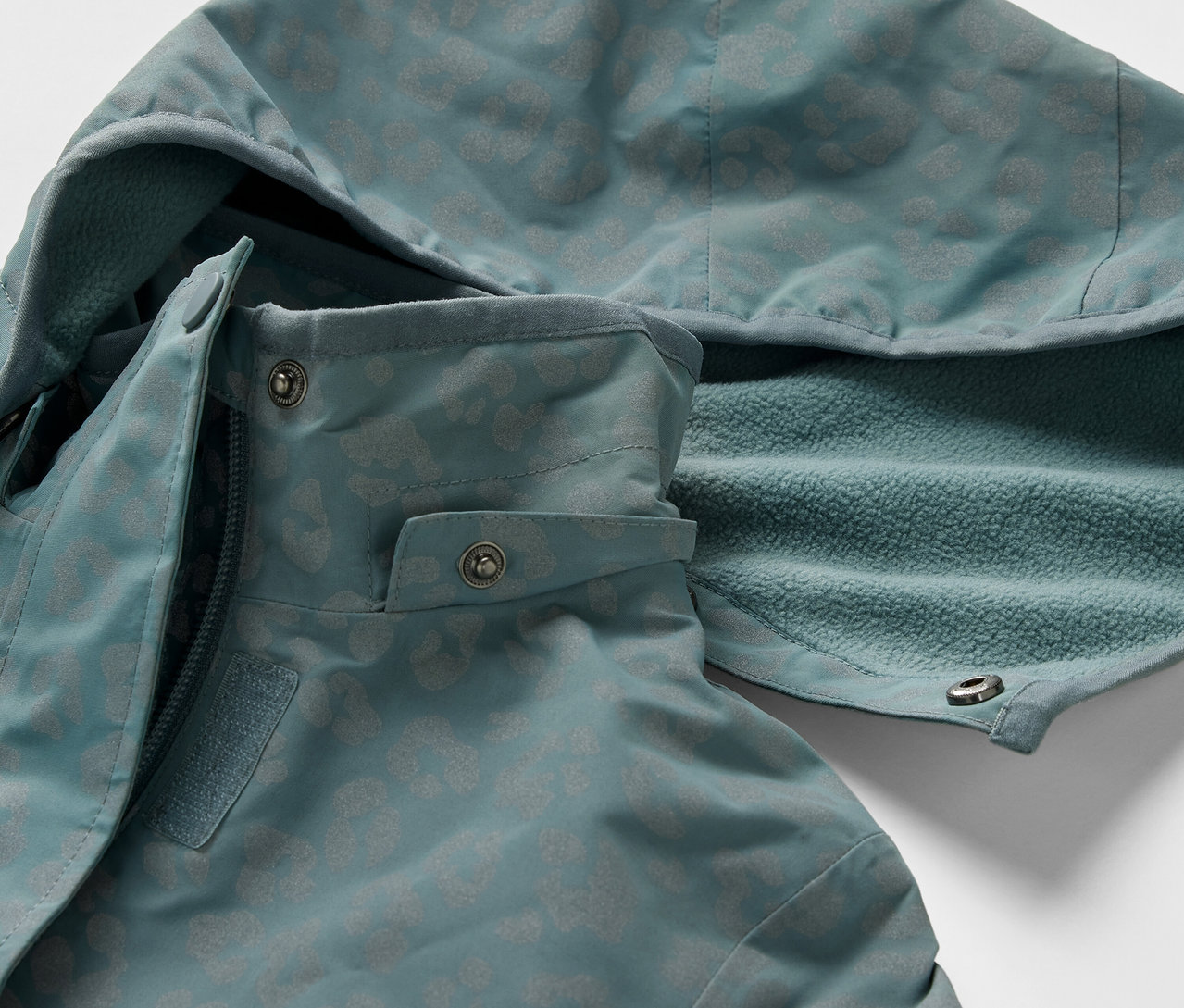 Detail dětské termo bundy do deště s reflexními prvky. Bunda má kapuci a zapínání na zip.