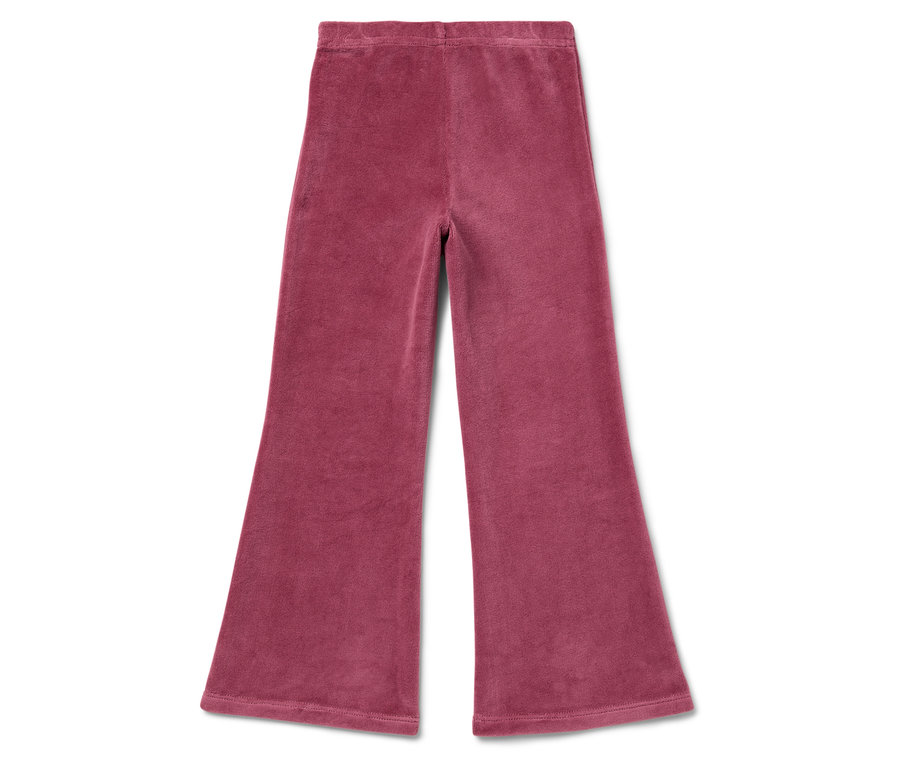 Růžové velurové kalhoty se zvonovými nohavicemi leží na bílém pozadí.