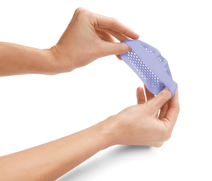 Ruce natahují fialovou silikonovou vložku s otvory.