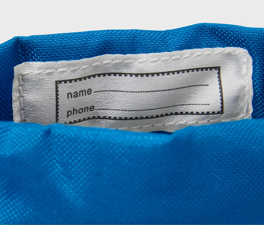 Na modré látce je našitá bílá cedulka s černým rámečkem na jméno a telefon.