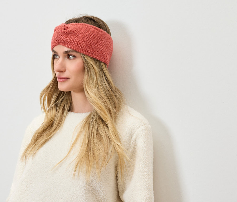 Žena s blond vlasy a korálovou pletenou čelenkou.