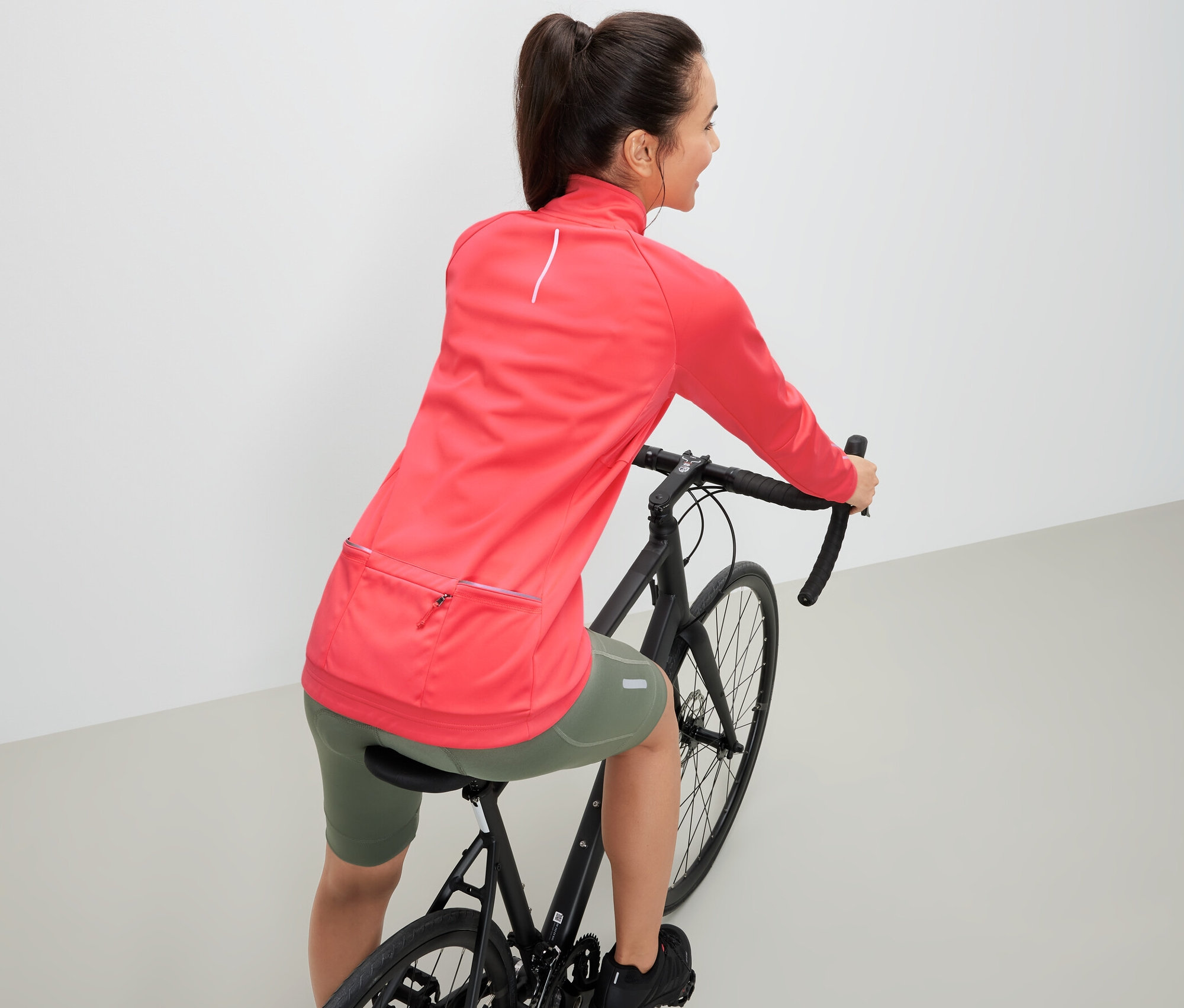 Žena na kole má na sobě funkční cyklistickou bundu.