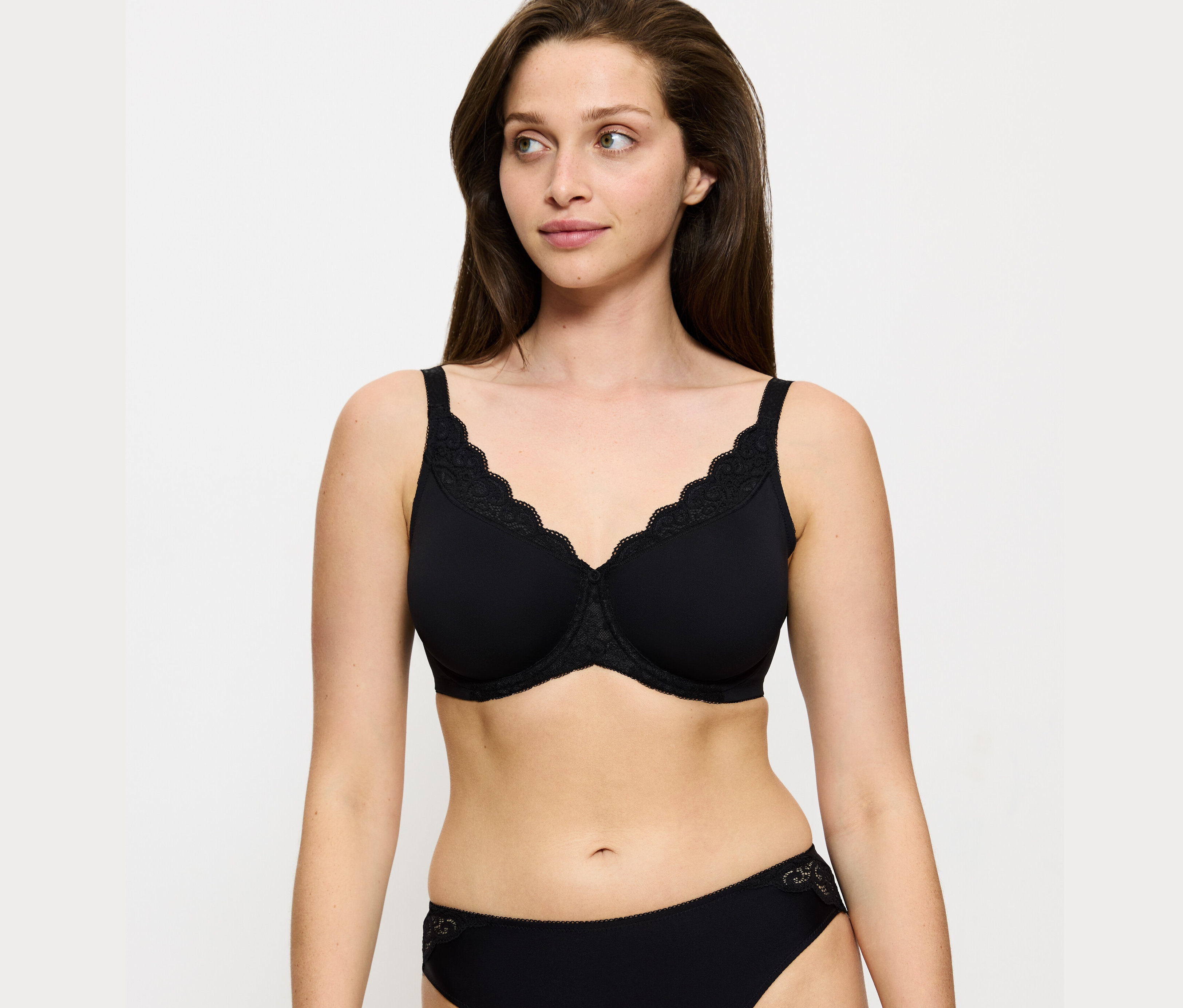 Žena má na sobě černou zmenšující podprsenku Triumph Amourette a černé kalhotky.