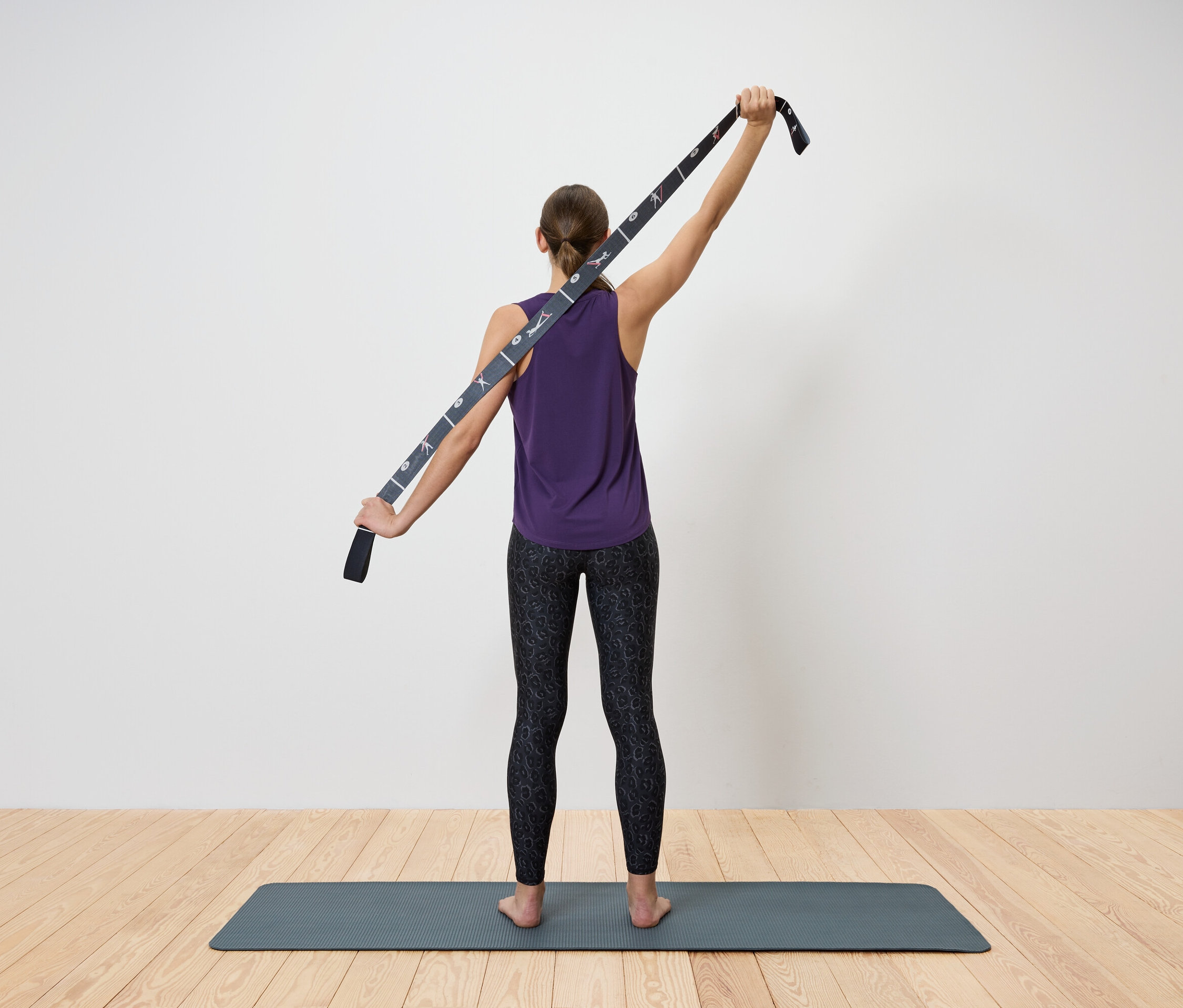 Žena protahuje horní část těla pomocí popruhu na jógu.