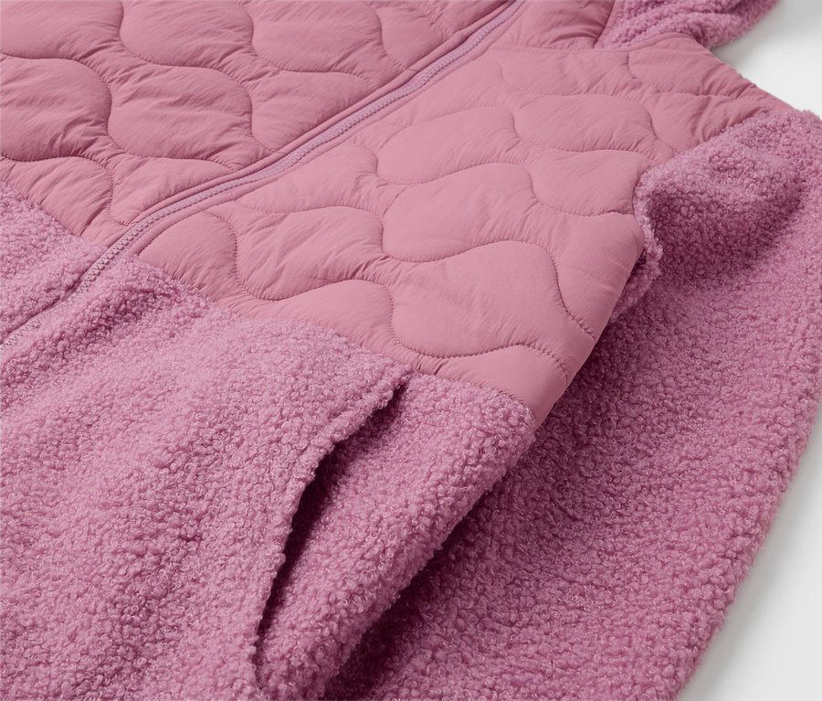 Detail růžové bundy s kapucí a kapsou.