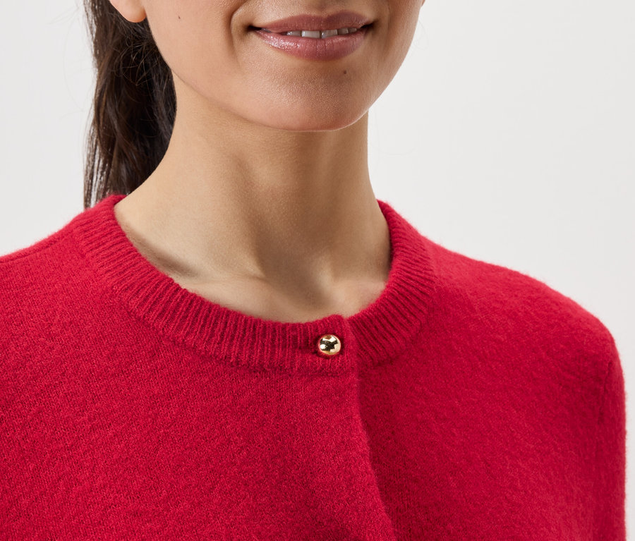 Detail ženy nosící červený kardigan.