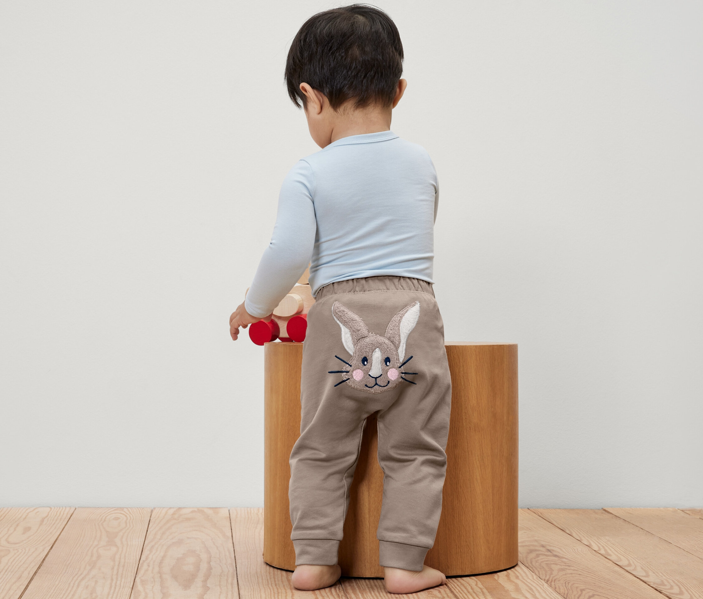 Chlapeček stojí zády, má na sobě kalhoty pro miminka s obrázkem králíka.