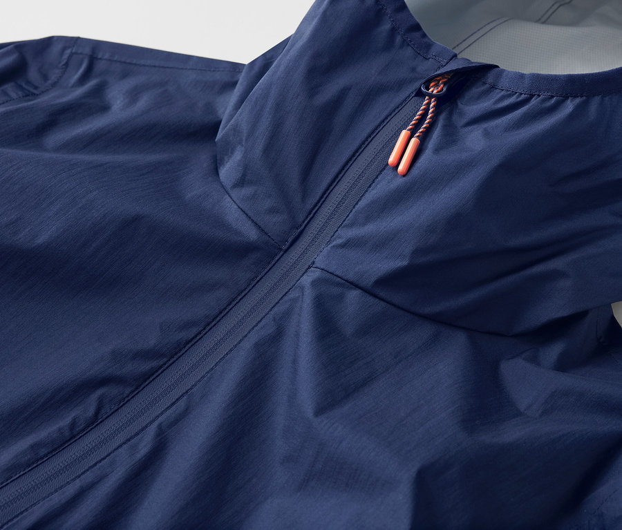 Detailní záběr na ultra lehkou bundu do deště »packable« s kapucí a zipem.