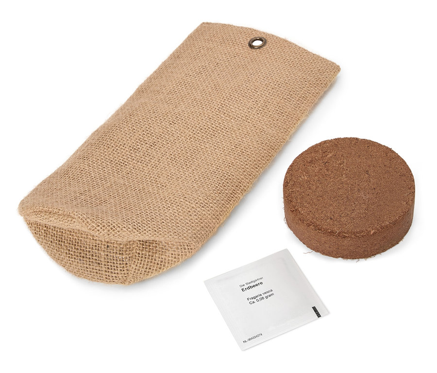 Hnědá jutová taška leží vedle kulaté hnědé tablety a malého bílého balíčku.