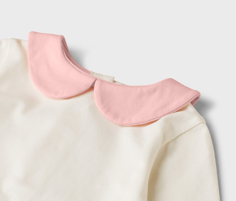 Detailní pohled na krémový top s růžovým kulatým límcem.