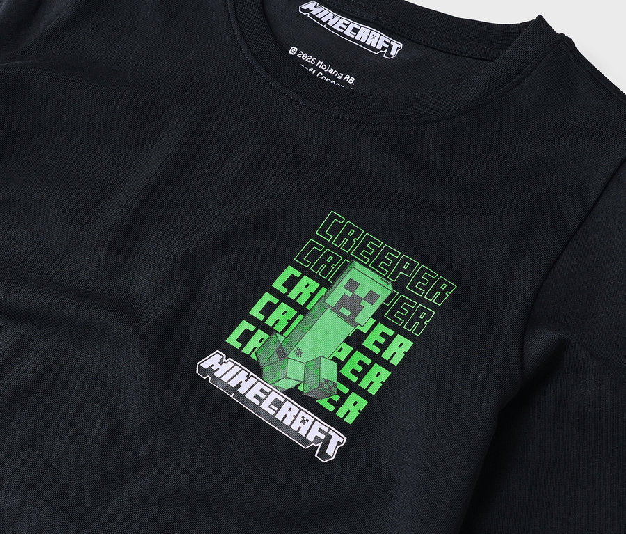 Detail černého trička s dlouhým rukávem se zeleným motivem Minecraft Creeper.