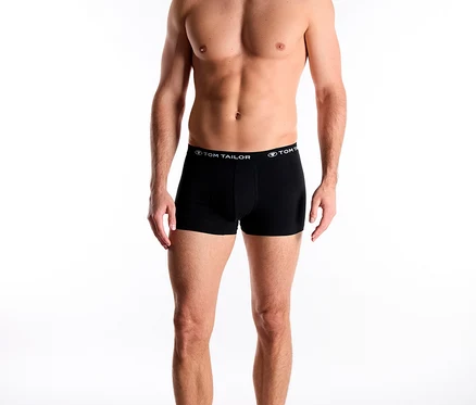 Muž stojí bosý a má na sobě černé boxerky značky Tom Tailor.
