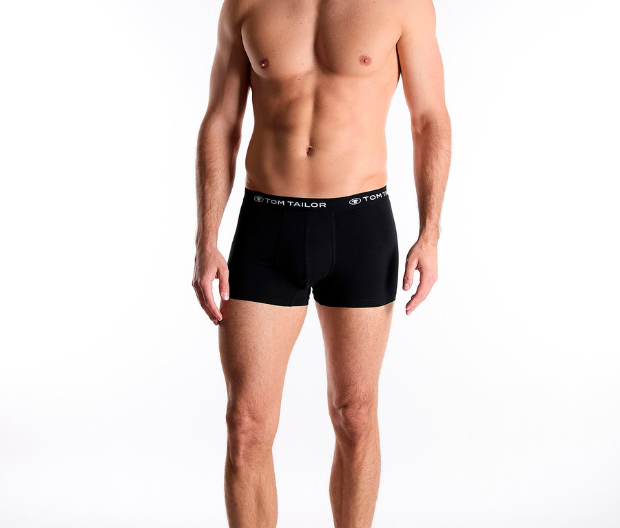 Muž stojí bosý a má na sobě černé boxerky značky Tom Tailor.