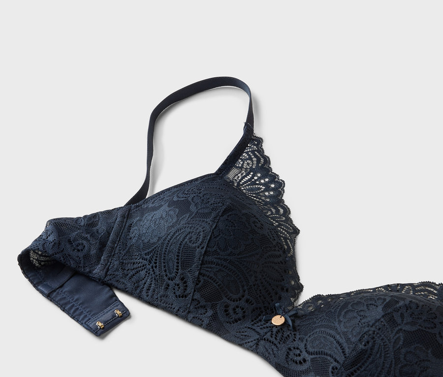 Detailní záběr na tmavě modrou krajkovou podprsenku s nastavitelným ramínkem.