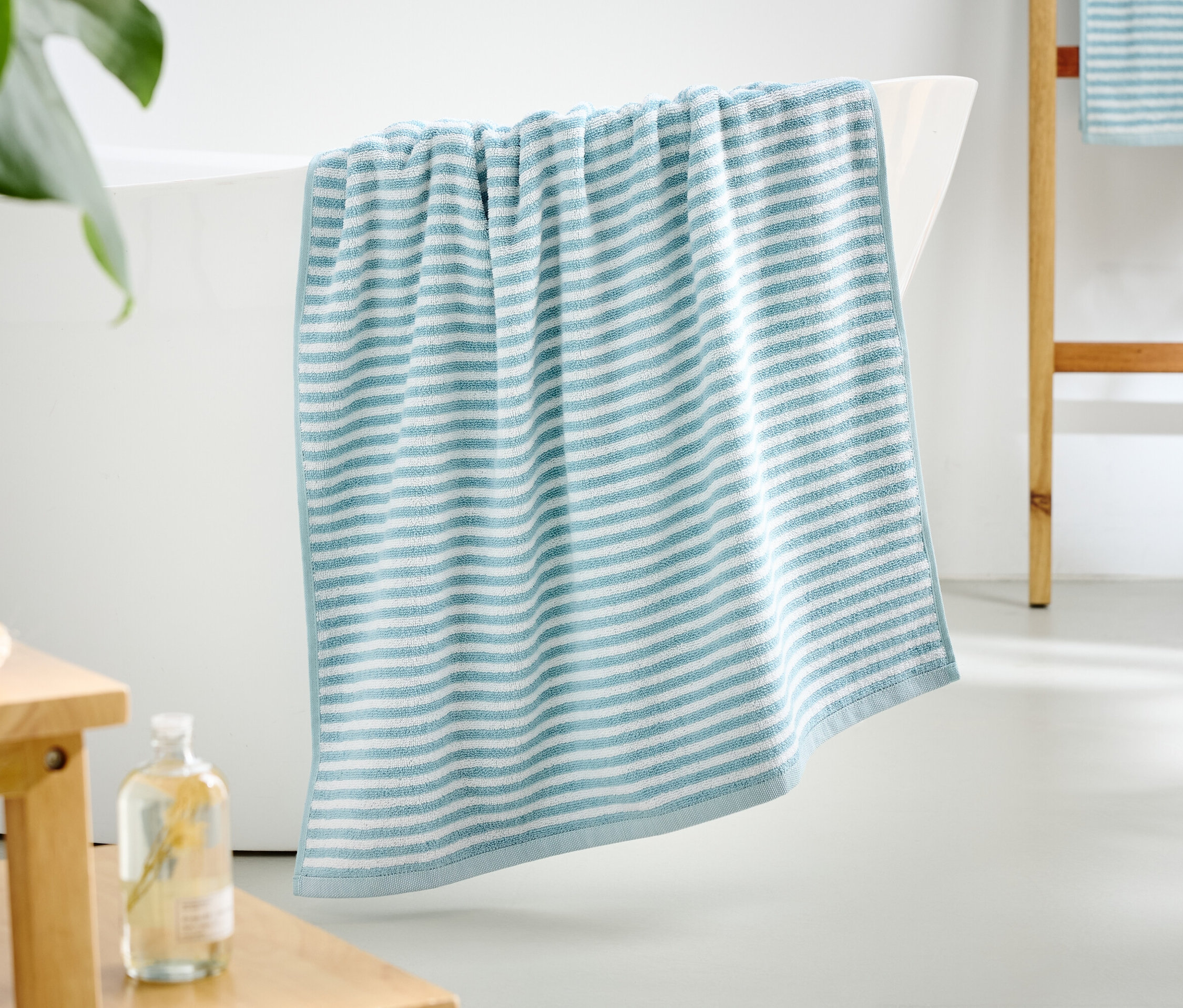 Modro-bílý pruhovaný ručník visí z okraje vany.