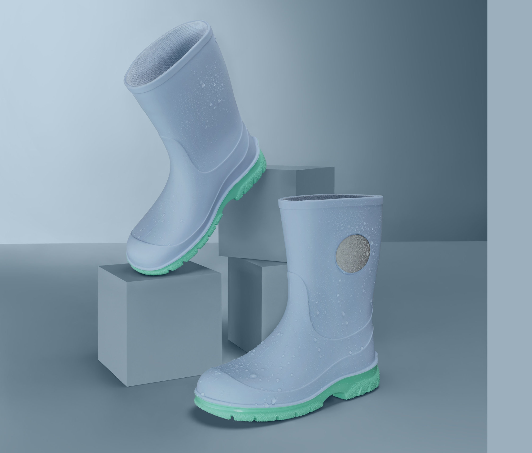 Dva světle modré holínky s limetkově zelenými podrážkami na šedých krychlích.