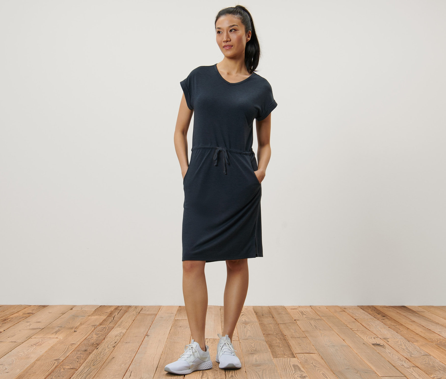 Žena pózuje v tmavě modrých outdoorových šatech.