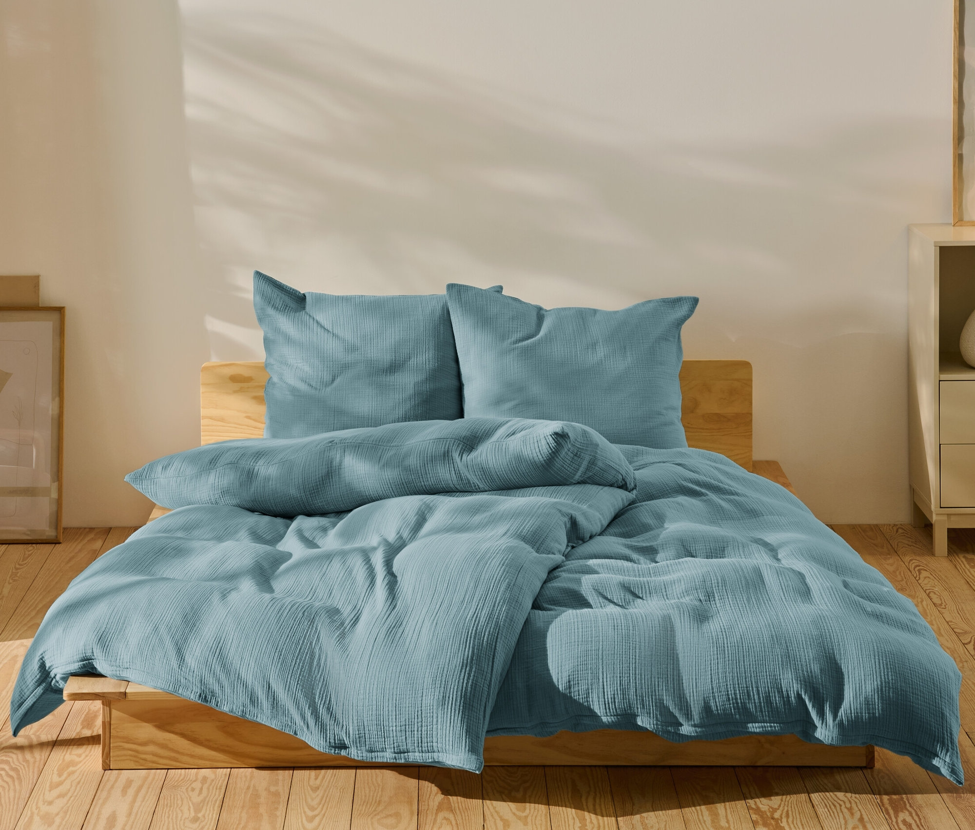 Modré mušelínové povlečení standardní velikosti a nadměrné velikosti na posteli.