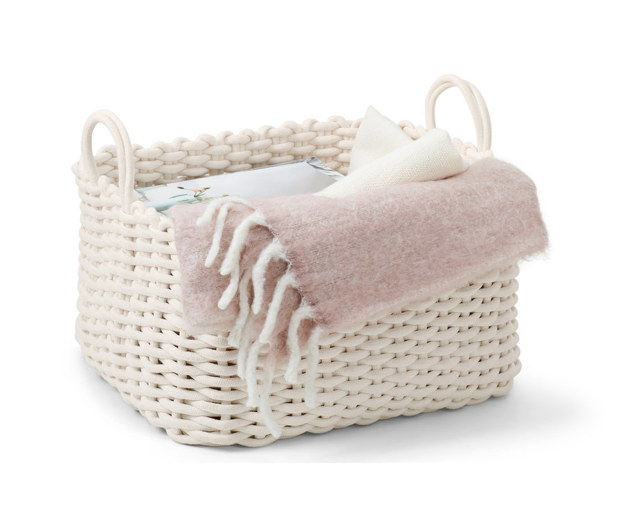 Velký pletený koš se 2 madly s přehozenou dekou a polštáři.