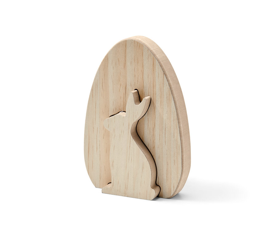 Dekorační zajíc z nelakovaného dřeva ve tvaru vejce, v němž je vyřezaný zajíc.