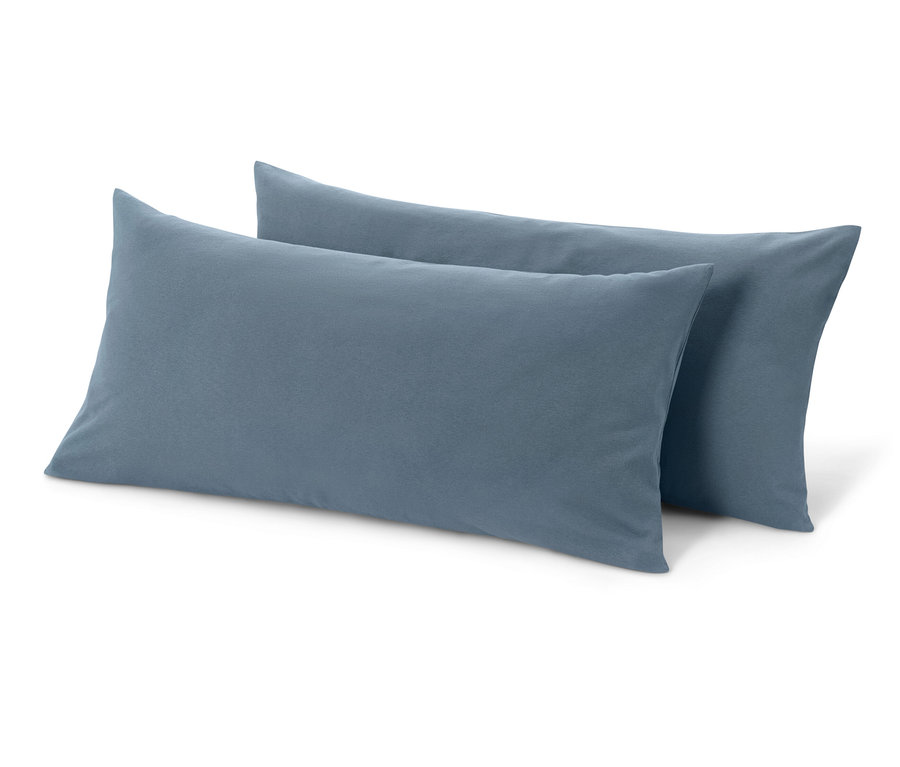 Dva modré žerzejové povlaky na polštáře leží na bílém pozadí.