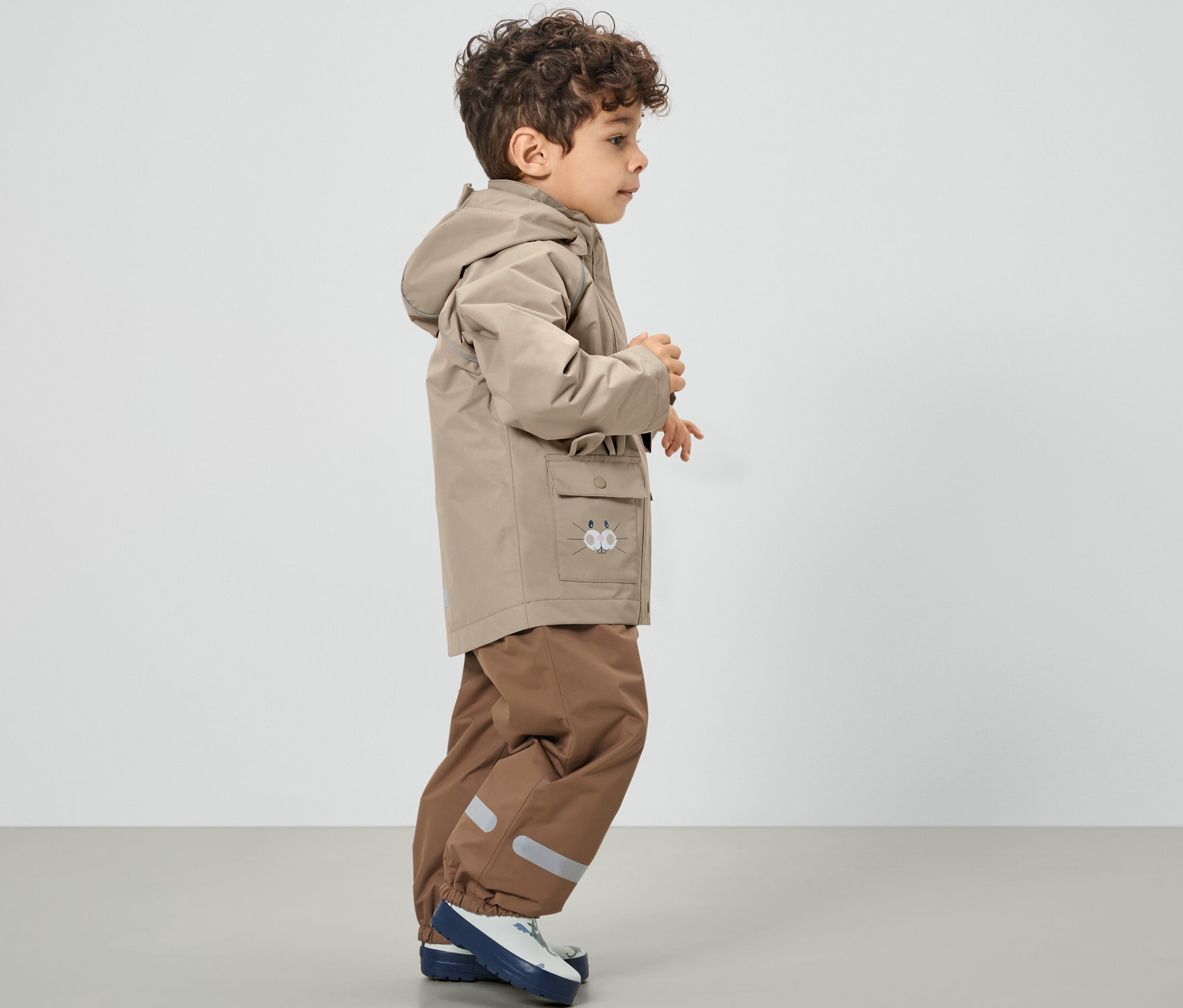 Chlapec v hnědé dětské bundě do deště.