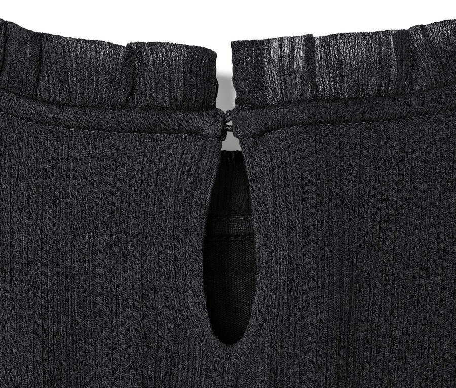 Detail dívčích šifonových šatů s volánem u krku a slzičkovým výstřihem.