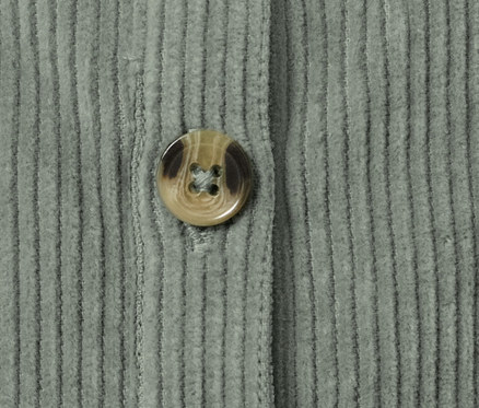 Detail dětských manšestrových kalhot s laclem se zapnutým knoflíkem.