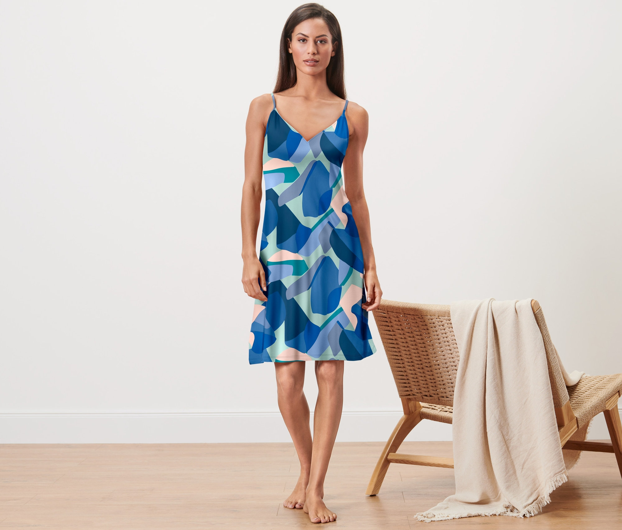 Žena stojí a má na sobě noční košili na ramínka s modrým vzorem.