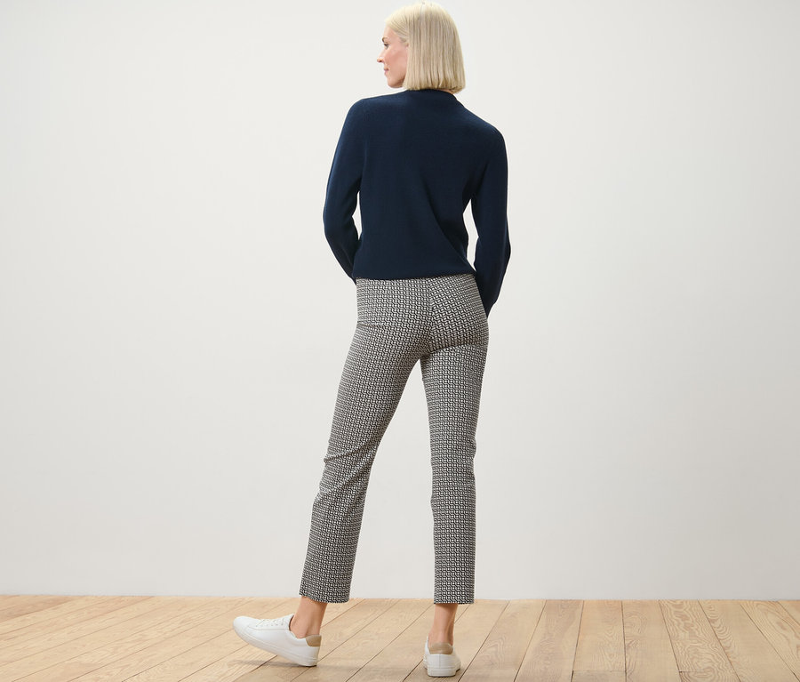 Žena stojí zády k fotoaparátu a má na sobě námořnicky modrý top a strečové kalhoty s potiskem.