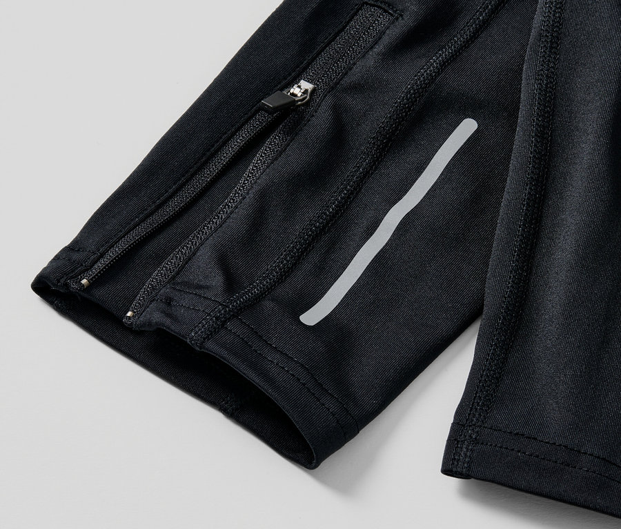 Detail černé běžecké legíny se zipem a reflexním proužkem.