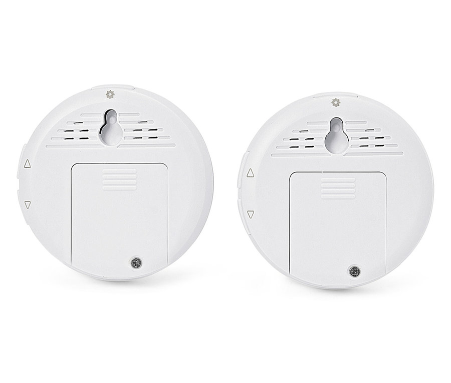 Dva bílé kulaté senzory s držáky na stěnu a kryty baterií.