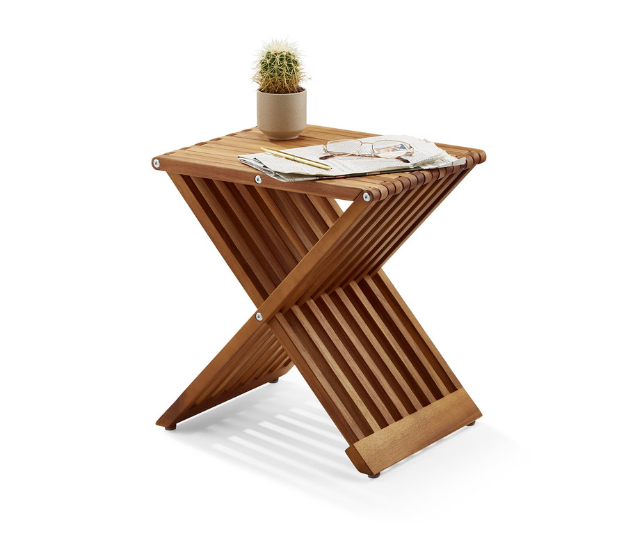 Na skládací stoličce leží kaktus v květináči, brýle, pero a kus papíru.