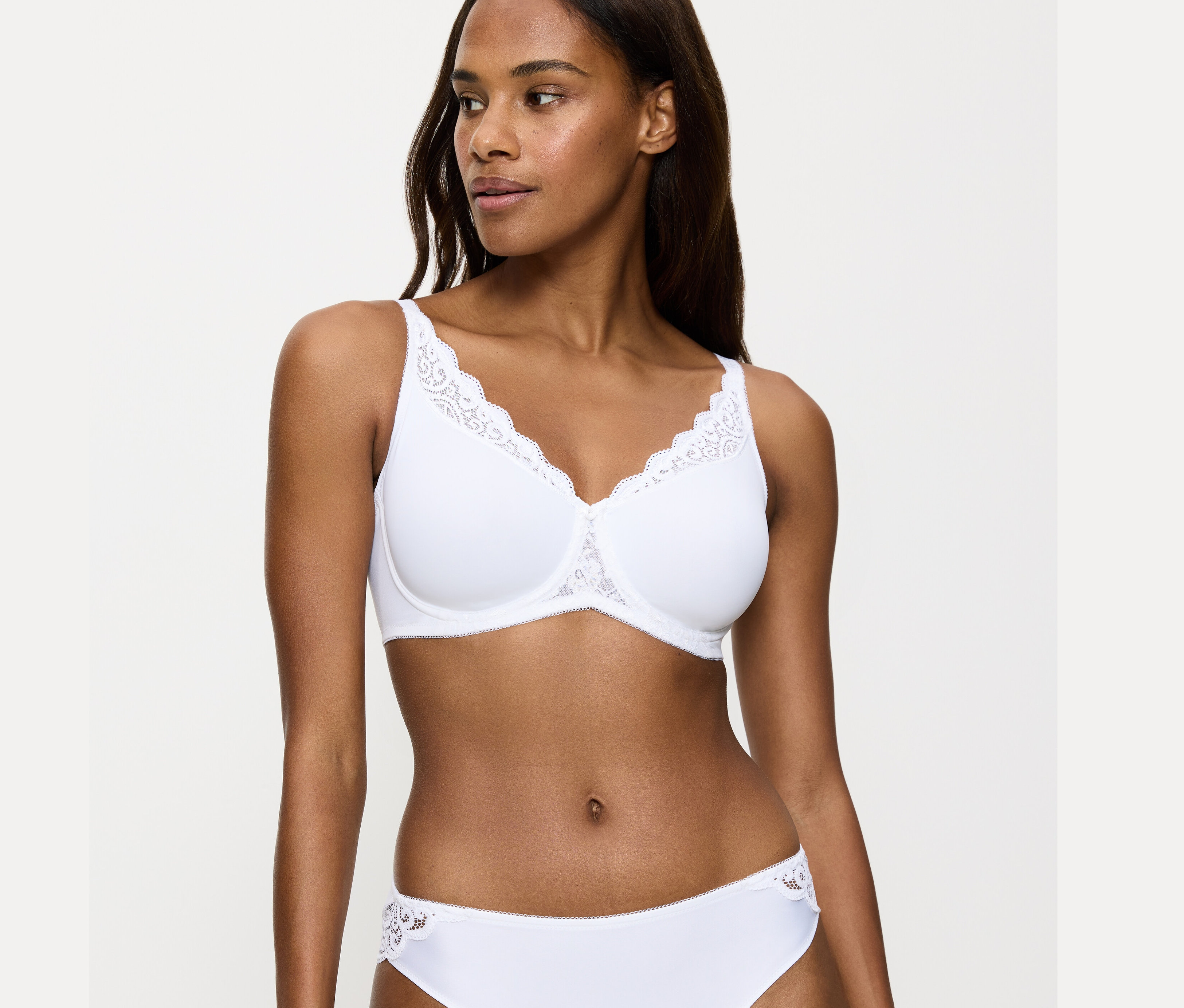 Žena má na sobě bílou zmenšující podprsenku Triumph Amourette.