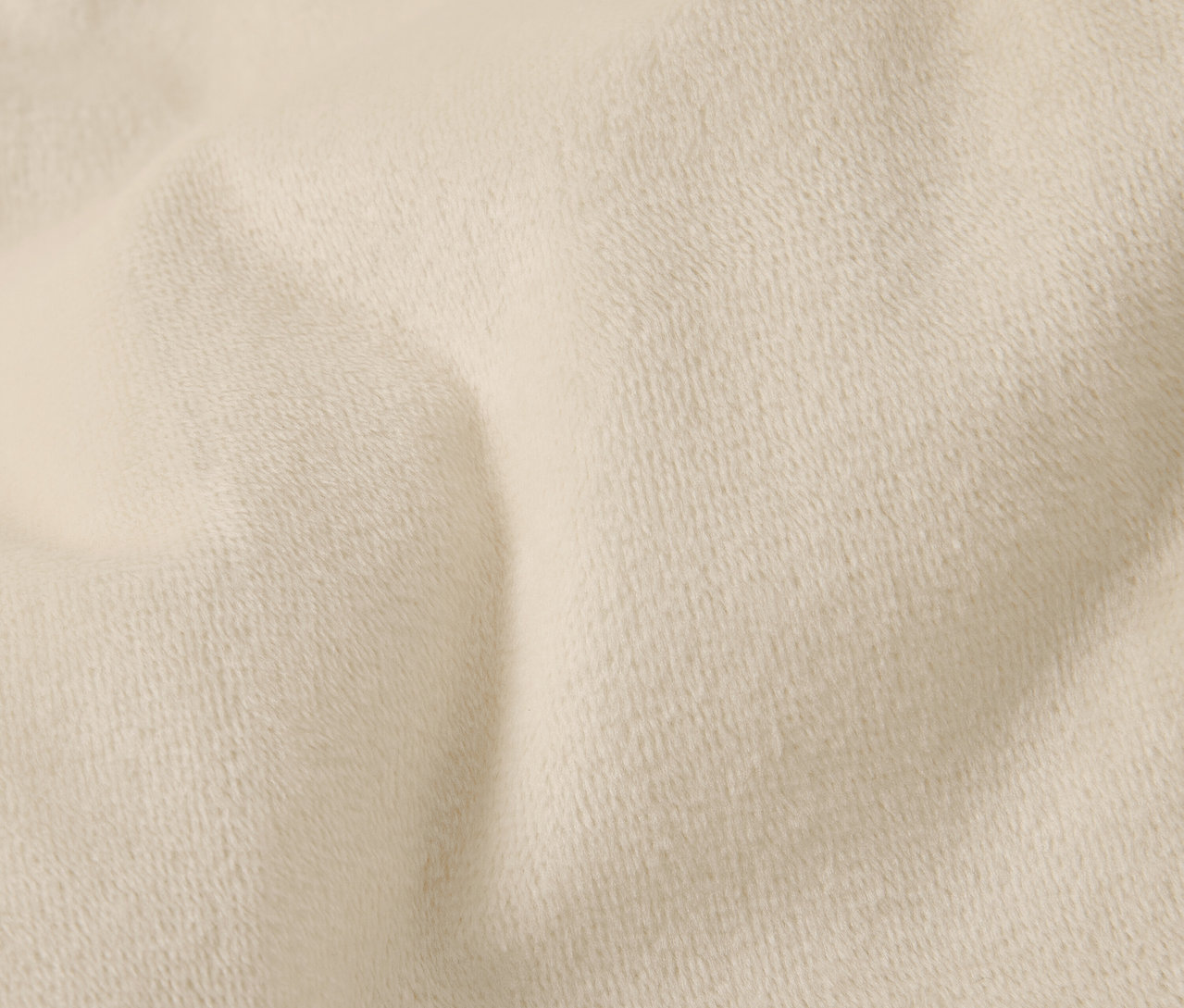 Detailní záběr krémové textilie s jemnou texturou a záhyby.