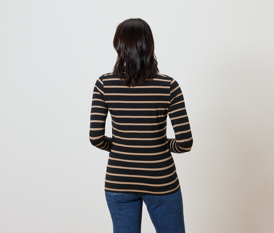 Zezadu je vidět žena s tmavými vlasy v pruhovaném tričku a modrých džínách.