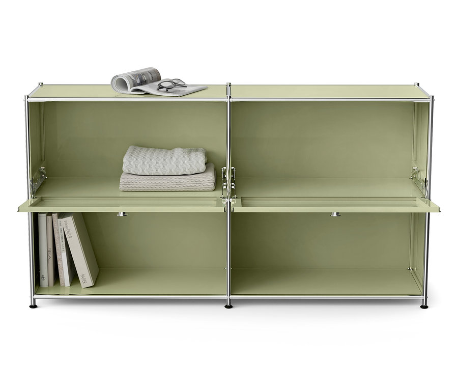 Zelená modulární skříň s knihami, dekou, brýlemi a novinami.