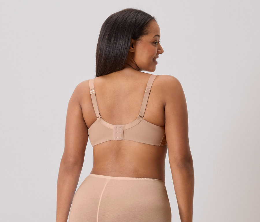 Pohled zezadu na ženu s dlouhými tmavými vlasy, která má na sobě tělovou podprsenku a odpovídající spodní prádlo.