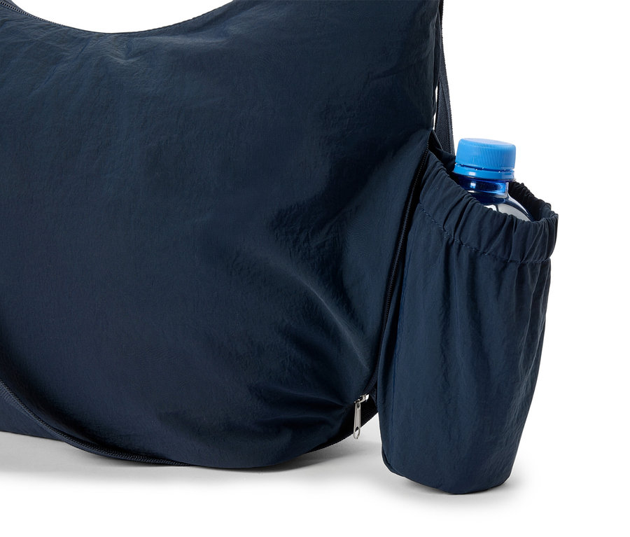 Detailní záběr na tmavě modrou nákupní tašku s lahví vody v boční kapse.