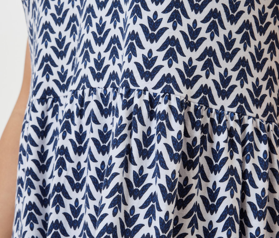 Detailní záběr na bílé šaty s modrým listovým vzorem.