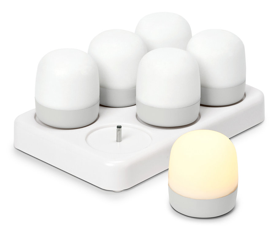 Pět bílých, kulatých nočních světel v nabíjecí stanici, vedle stojí další svítící noční světlo.