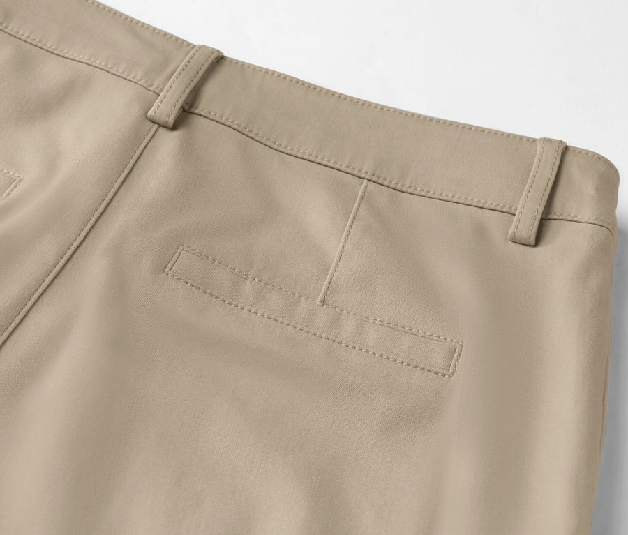 Detailní záběr zadní části béžových kalhot s kapsou na hýždích a poutky na opasek.