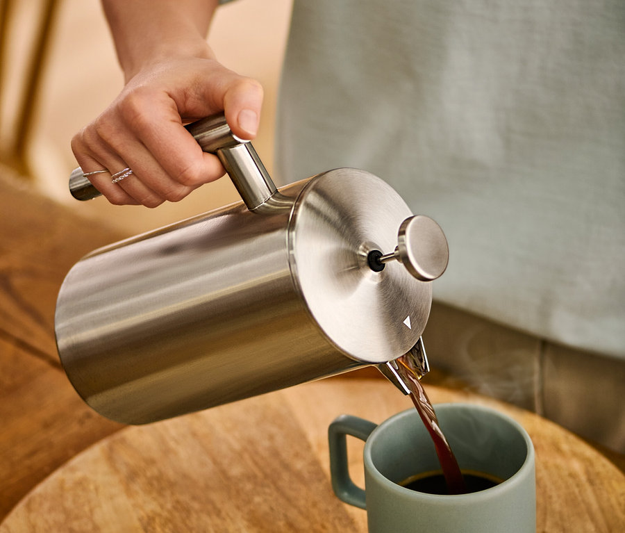 Žena nalévá kávu z dvoustěnné konvice french press z ušlechtilé oceli o objemu 900 ml do hrnku.