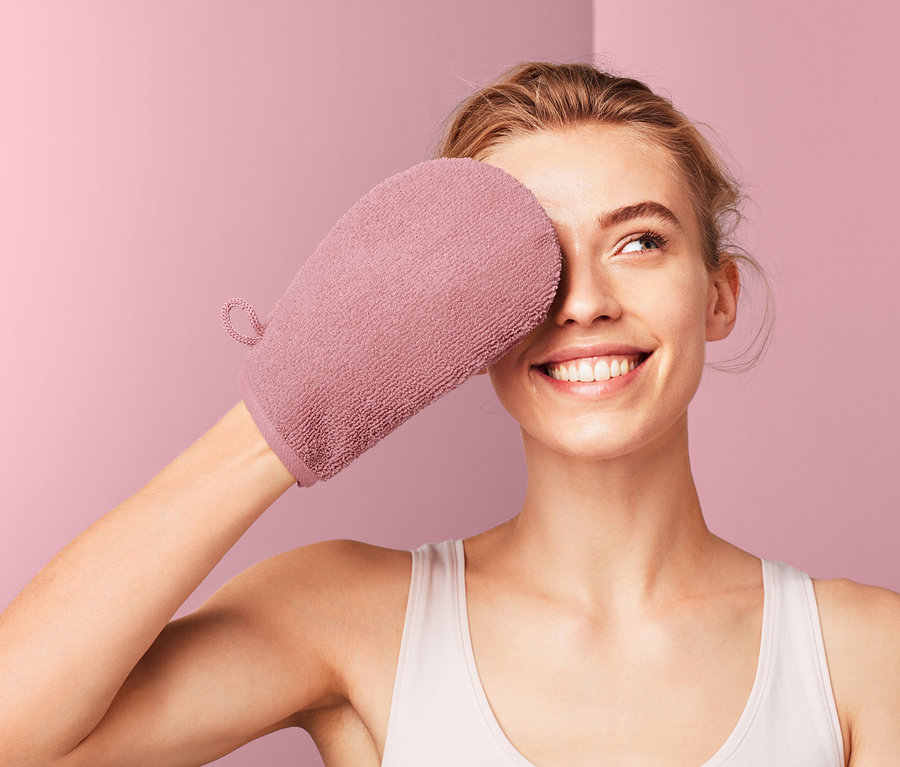 Žena si zakrývá oko odličovací rukavicí z mikrovlákna.