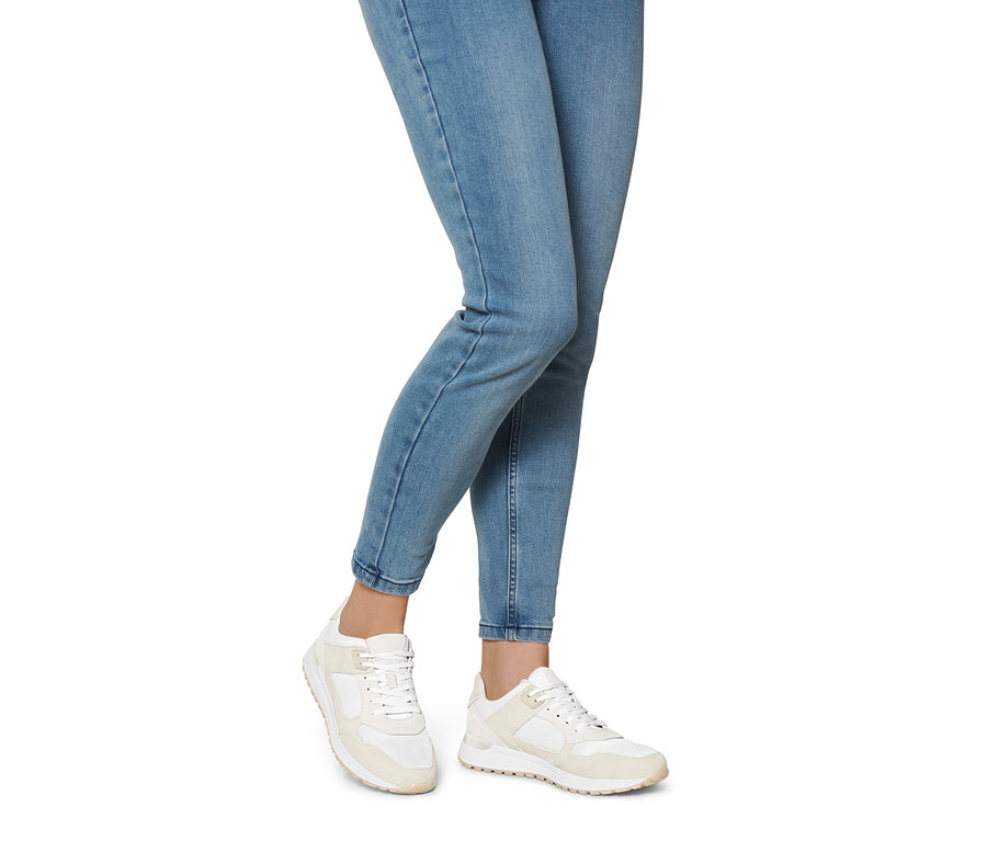 Nohy ženy v džínách a botách sneaker z velurové kůže.