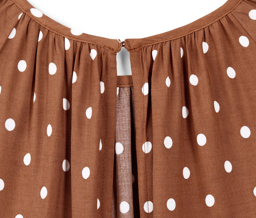 Detail hnědých puntíkovaných midi šatů.