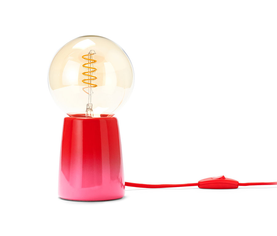 Červeno-růžová LED stolní lampa se žárovkou a červeným kabelem.