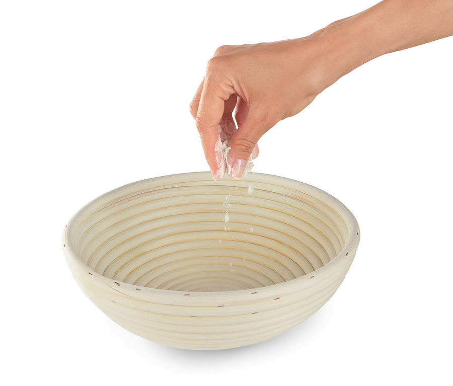 Ruka sype mouku do kulaté ošatky na kynutí těsta.