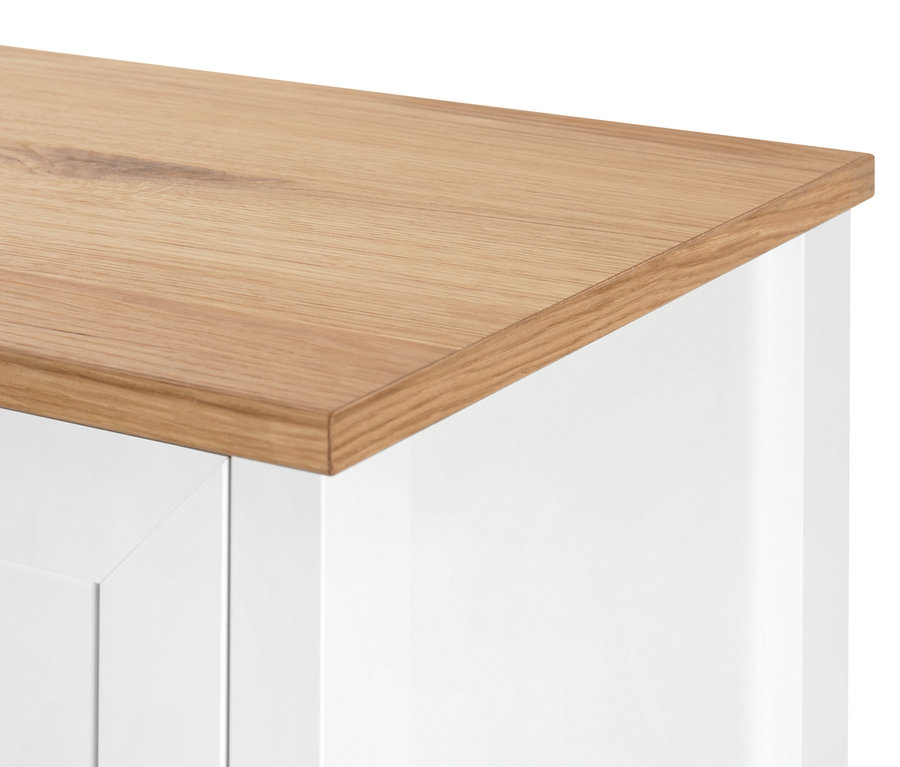 Detail horní části bílé komody s dřevěnou deskou.